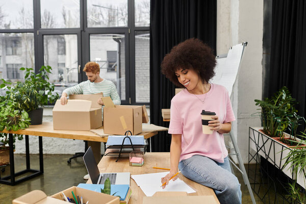 Two people pack boxes and organize their stylish workspace, enjoying the process together.