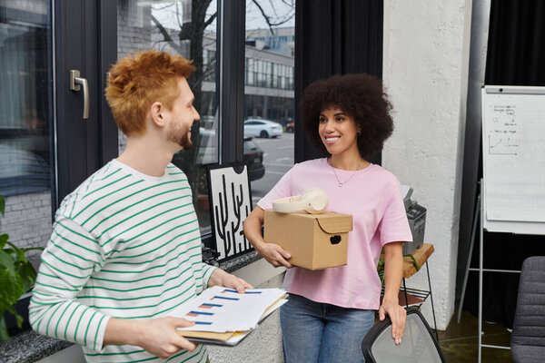 Two people pack and unpack items as they prepare to move in a modern office.