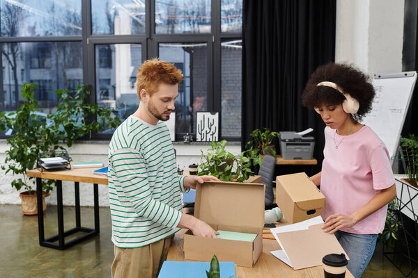Two people pack and unpack in a modern office filled with plants.