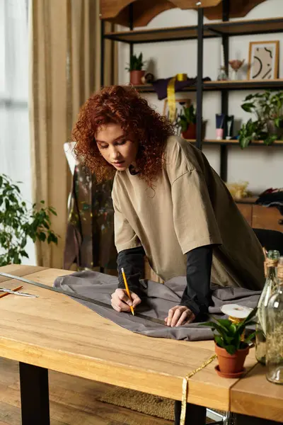 Yetenekli genç bir kadın zarif atölyesindeki gri kumaşa titizlikle şablon çiziyor..