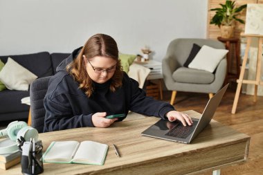 Rahat bir evde, Down sendromlu kendine güvenen genç bir kadın telefonunu ve laptopunu kullanır..