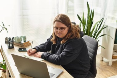 Down sendromlu genç bir kadın masasında sıcak, davetkar bir yerde yazıyor..