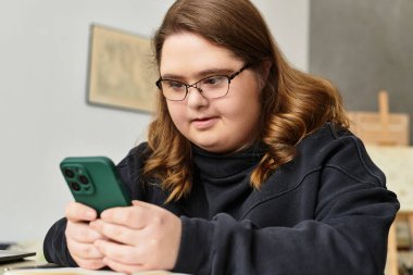 Genç bir kadın akıllı telefonuyla rahatça iletişim kuruyor, rahatlatıcı bir ev ortamının tadını çıkarıyor..