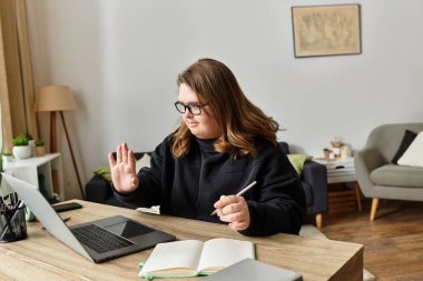 Rahat bir yerde Down sendromlu genç bir kadın bilgisayarını masasında kullanıyor..