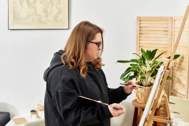 Rahat bir yaşam alanında, Down sendromlu kendine güvenen genç bir kadın neşeyle resim yapar..