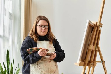 Elinde bir paletle, genç bir kadın sanatsal ruhunu keşfediyor, evdeki yaratıcılığını ifade ediyor..