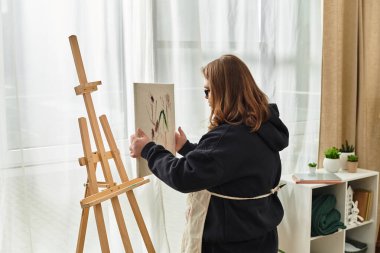 Down sendromlu genç bir kadın, rahat evinde resim yapmaya hazırlanıyor..