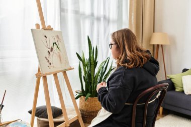 Down sendromlu genç bir kadın sıcak ve rahat bir ortamda sanat yaratıyor..