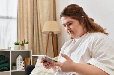 Down sendromlu kendinden emin genç bir kadının tabletinde okuduğu gibi evde rahat bir öğleden sonra..