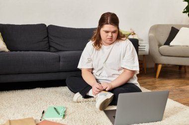 Down sendromlu kendine güvenen genç bir kadın evde rahatlıyor ve dizüstü bilgisayarına odaklanıyor..