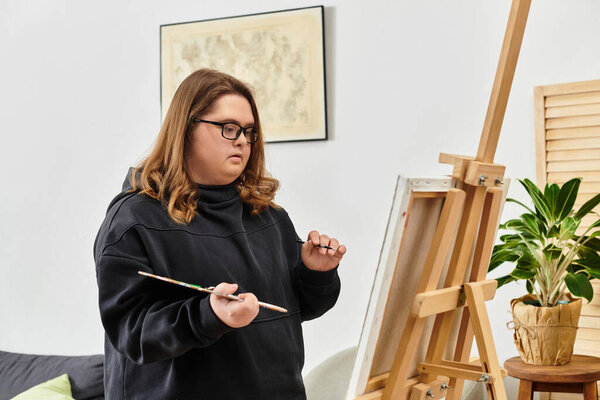 Молодая женщина с синдромом Дауна наслаждается живописью дома, выражая свое творчество с гордостью.