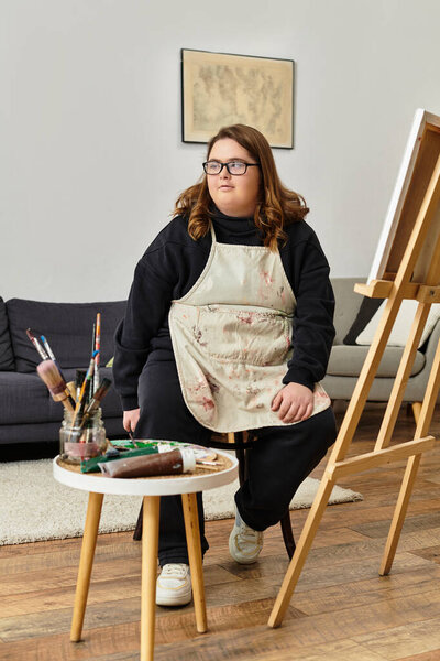 Молодая женщина создает искусство дома, в окружении предметов живописи в непринужденной обстановке.