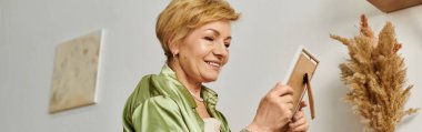 Gülümseyen bir son sınıf öğrencisi, rahat evinde çerçeveli bir anıya değer verir..