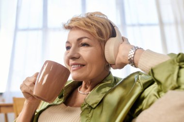 Son sınıf öğrencisi kadın kulaklık takıp sıcak bir içki yudumluyor. İçeriden neşe ve sükunet yayıyor..