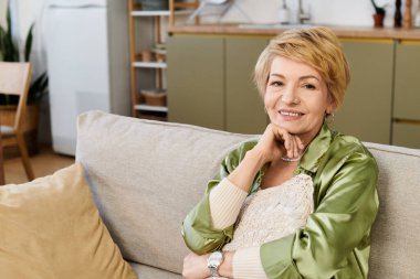 Neşeli, son sınıf öğrencisi bir kadın şık oturma odasındaki kanepesinde rahatça oturur..