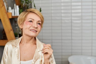 Neşeli bir gülümseme ile, güzel bir son sınıf kadını, güzel banyosunda kendine bakımı kucaklıyor..