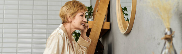 Senior woman admires herself in a mirror while enjoying a quiet moment at home.