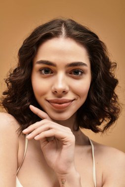 Güzel genç bir kadın, stüdyo ortamında güzel cildini gösterirken gülümsüyor..