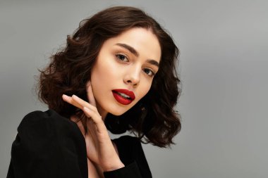 Güzel genç bir kadın büyüleyici diş tellerini ve kırmızı dudaklarını sergiliyor, kendine güveni ve tarzı ile.