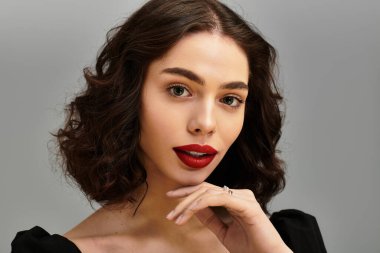 Kıvırcık saçlı, kırmızı dudaklı, kendine güvenen genç bir kadın..