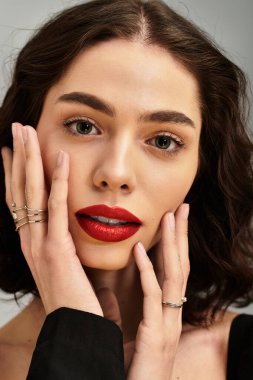 Genç bir kadın, göz alıcı kırmızı dudaklarıyla güzelliğini sergiliyor, diş telleriyle güzelce çerçevelenmiş..
