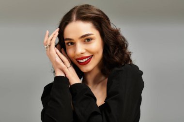Kendine güvenen bir kadın kırmızı dudaklarıyla parlar ve yumuşak bir arka planda sevimli diş telleriyle..