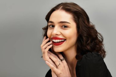 Parlak kırmızı dudakları ve diş telleri olan genç bir kadın zarif poz verirken ışıl ışıl gülümsüyor..