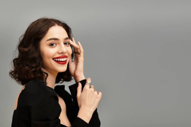 Çekici genç bir kadın bulaşıcı gülüşünü gösteriyor diş telleri ve canlı kırmızı dudaklarla süslenmiş.