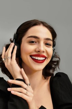 Telleri ve kulaklıkları olan neşeli genç bir kadının müzik zevki için canlı kırmızı dudakları vardır..