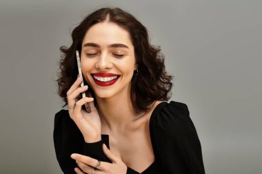 Telleri ve parlak kırmızı dudakları olan ışıl ışıl genç bir kadın telefonuyla neşeli bir sohbete girişiyor..