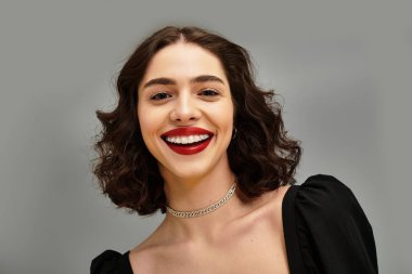 Genç bir kadın, canlı kırmızı dudakları ve büyüleyici diş telleriyle gülümserken kendine güvenir..