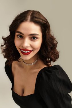 Diş telleri ve kırmızı dudakları olan genç bir kadın büyüleyici gülüşüyle kendine güveniyor..