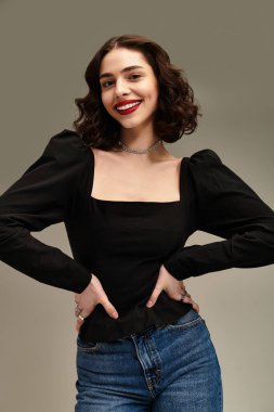 Parlak gülümseyen diş telleri ve kırmızı dudakları olan kadın gri bir arka plana karşı güvenli bir şekilde poz veriyor..