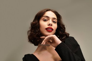 Genç bir kadın diş tellerini ve kalın kırmızı dudaklarını göstererek büyüleyici bir duruş sergiliyor..