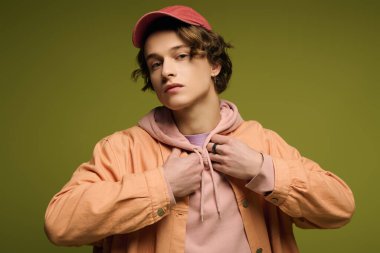 Şık bir genç adam canlı bir arkaplanda poz veriyor, gençlik kültürünü somutlaştırıyor..