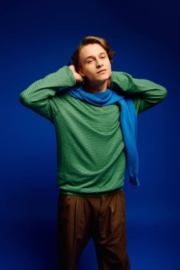 Şık giyinen genç bir adam, çağdaş moda eğilimlerini sergileyerek kendine güvenerek poz veriyor..