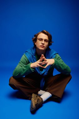Şık bir genç adam yerde oturuyor, kendine güvenen çağdaş gençlik kültürünü somutlaştırıyor..