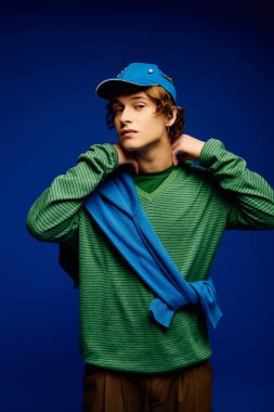 Genç bir adam, yeşil ve mavi aksanlı şık bir kıyafete güvenir..