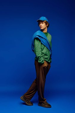 Tarz sahibi genç bir adam modaya uygun giyinmiş, modern modaya uygun şekilde poz verir..