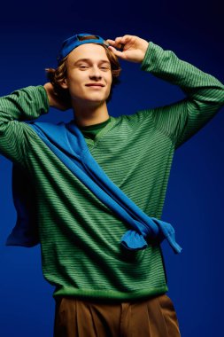 Moda kıyafetli şık genç adam neşeli bir poz veriyor, çağdaş gençlik kültürünü somutlaştırıyor..