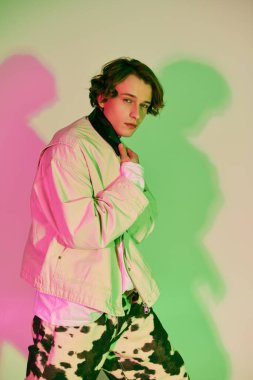 Moda elbiseli genç bir adam kendine güvenerek poz veriyor, benzersiz bir stil ve modern yetenek sergiliyor..