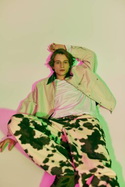 Modaya uygun genç bir adam şık bir şekilde poz verir. Etrafı canlı renklerle çevrilidir..