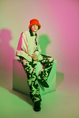 Renkli kova şapkalı genç bir adam yaratıcı bir sahnede modern gençlik kültürünü ön plana çıkarıyor..