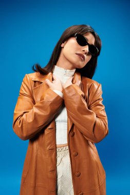 Modaya uygun genç Asyalı bir kadın zarif bir şekilde poz veriyor, şık kıyafetlerini ve büyüleyici tarzını sergiliyor..