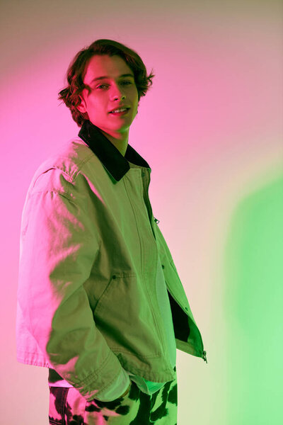 A stylish young man stands confidently in trendy attire, illuminated by vibrant colored lights.