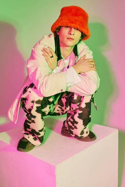 Молодой человек в модном наряде уверенно позирует, сочетая красочные элементы с неповторимым стилем.