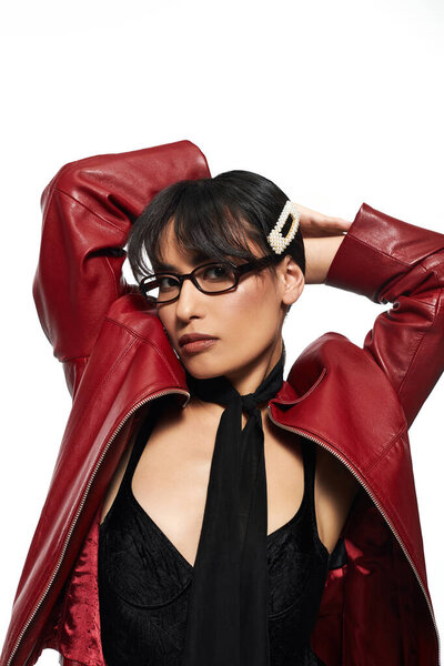 A stylish young asian woman poses confidently, displaying her fashionable jacket and accessories.