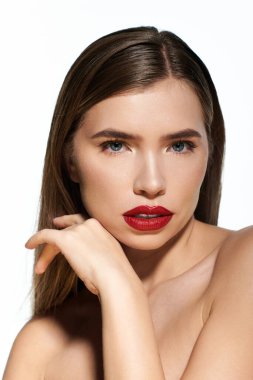 Şık genç kadın kendine güvenen bir pozla güzelliğini sergiliyor, canlı kırmızı dudaklarını vurguluyor..