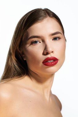 Kendine güvenen genç kadın zarif pozlar veriyor çarpıcı özelliklerini ve canlı rujunu sergiliyor..