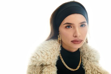 Genç bir kadın şık bir kıyafet modelliyor. Parlak bir ortamda kendine güven ve zarafet yayıyor..
